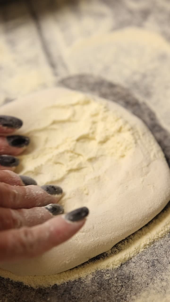 Primo piano di una mano che preme un impasto fresco per pizza con la farina