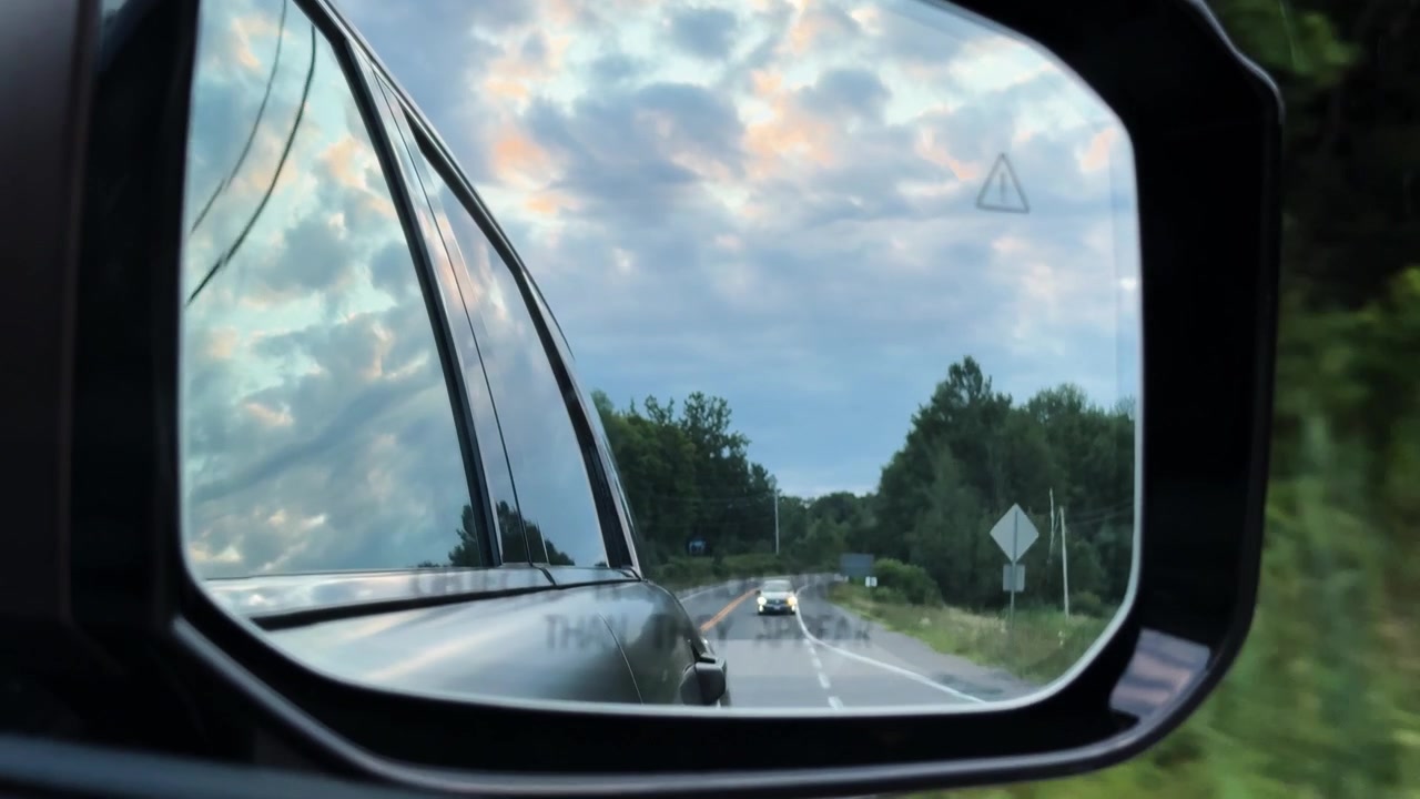 Moving rearview view of a distant car following before taking a rural exit.