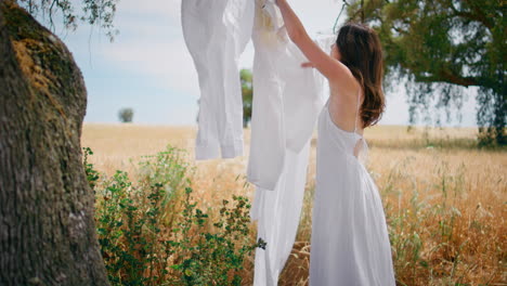 rural lady correcting laundry rope at summer field. country girl putting basket