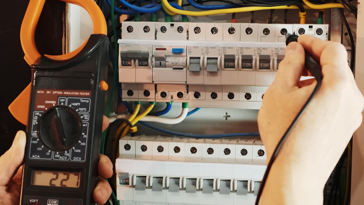 los electricistas ponen las manos a probar la corriente eléctrica en el panel de control. el ingeniero electricista trabaja midiendo el voltaje y la corriente de la línea eléctrica en el control del gabinete eléctrico.