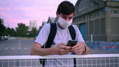 Hombre-Con-Mascarilla-Sonriendo-Mientras-Recibe-Un-Mensaje-Por-Teléfono-Afuera-Cerca-Del-Puerto-De-Puerto-Ingeniero-Blanco,-Buenos-Aires,-Argentina