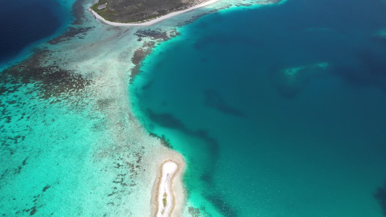 Turquoise waters and a narrow sandy path separating two vibrant blue ocean sides, aerial view