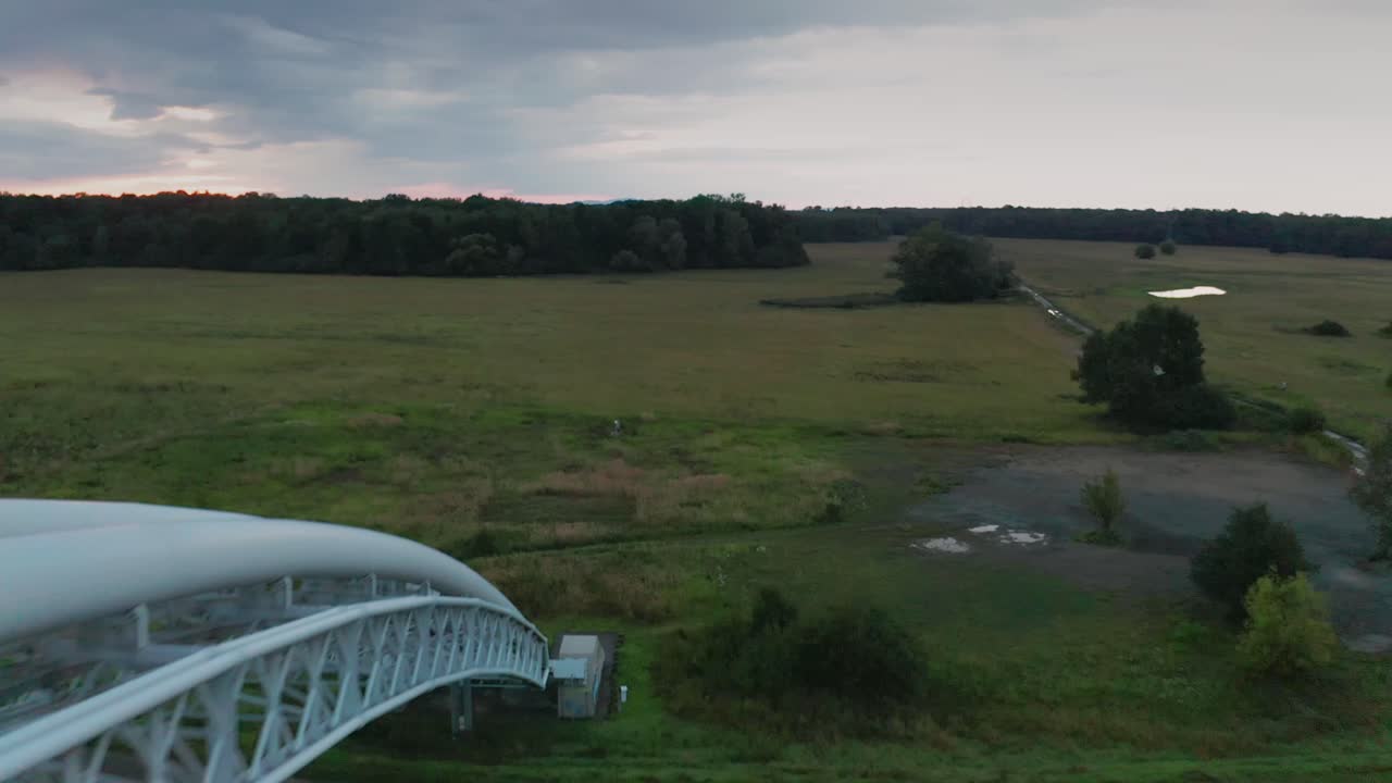 Flying above gas pipes across calm river Morava in Slovakia. Aerial sunset footage of a gas pipe bridge.