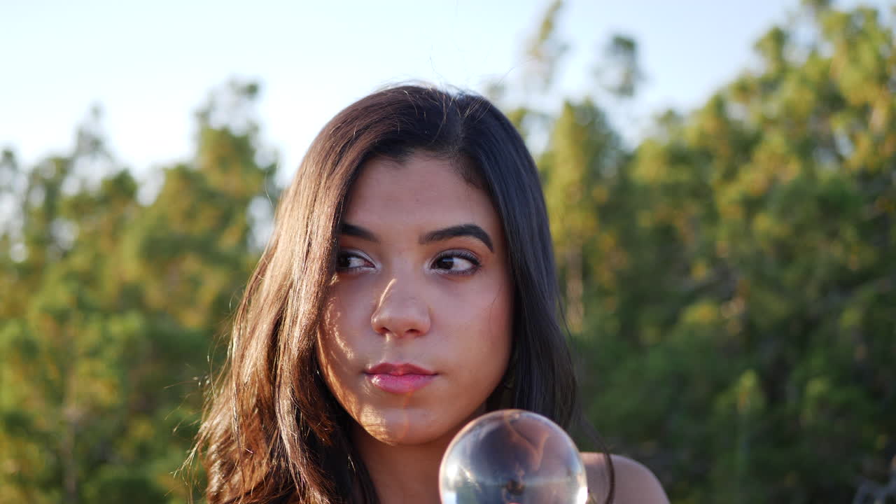 A beautiful woman in a mystical fantasy land casting a spell or enchantment and staring with smiling eyes at her magic crystal ball CLOSE UP