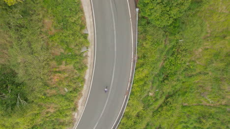 Drone-Birdseye-View-Over-Cyclist-Riding-Bike-Along-Rural-Australian-Countryside-Road,-4K-Slow-Motion