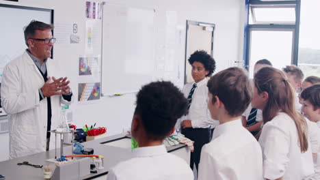 male high school tutor teaching students wearing uniforms in science class