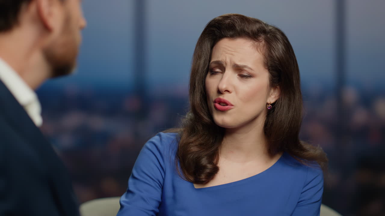 Primo piano di un conduttore che guarda un ospite uomo con compassione, ascoltando una storia triste in un programma televisivo.