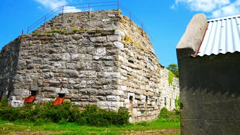 Old-abandoned-landmark-stone-mill-restoration-buildings-on-Welsh-industrial-coastal-countryside-dolly-left-reveal