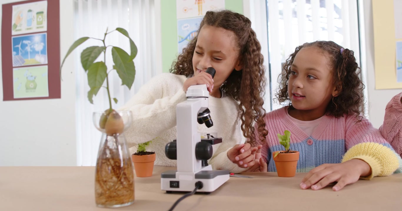 African American child girls chatting and left girl using microscope in lab examining roots