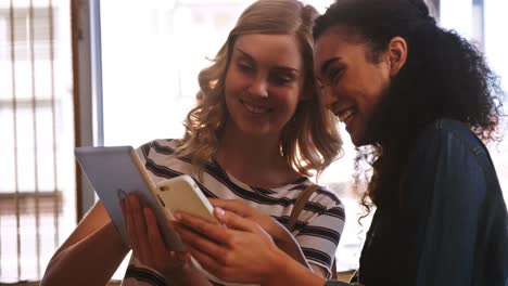 Hübsche-Frauen,-Die-Mobiltelefon-Und-Digitales-Tablet-Nutzen