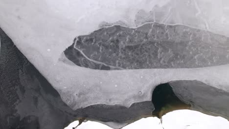 aerial shot of various shapes on the ice surface of a frozen lake