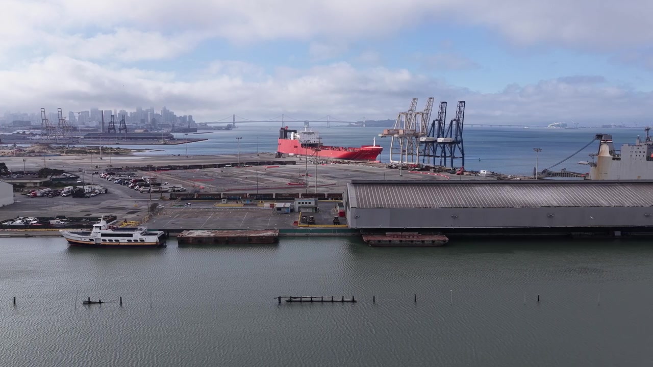 Buque de carga atraca en un puerto concurrido cerca del horizonte de San Francisco y el Puente de la Bahía