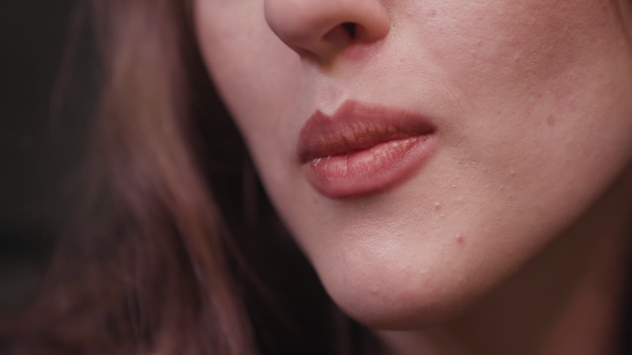 Extreme close up of lady using tongue and mouth to eat creamy waffle from fork, showing detail of lips and dessert texture in intimate food moment during indoor meal
