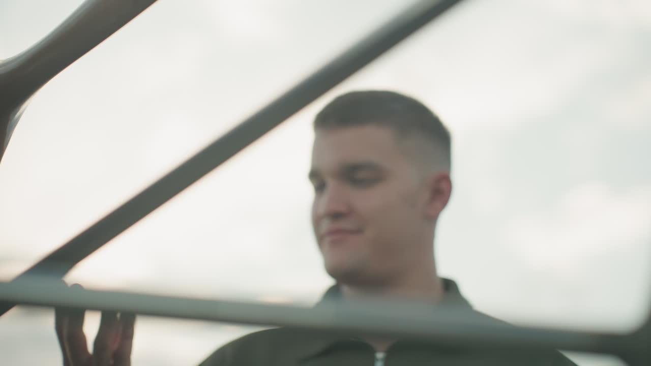 close up of man hand cleaning wooden fan blade near metal frame under soft sky lighting, focus on tactile motion and textured grain, emphasising careful maintenance ritual in gentle outdoor setting