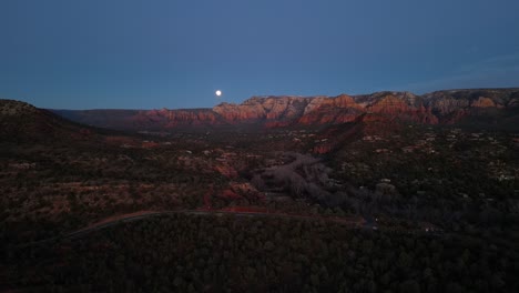 vista aérea que revela el crepúsculo de la ciudad de sedona y las rocas rojas mientras la luna se eleva sobre oak creek