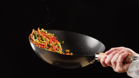 chef stir-frying vegetables in a wok