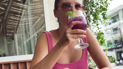 mujer disfrutando de un cóctel púrpura al aire libre
