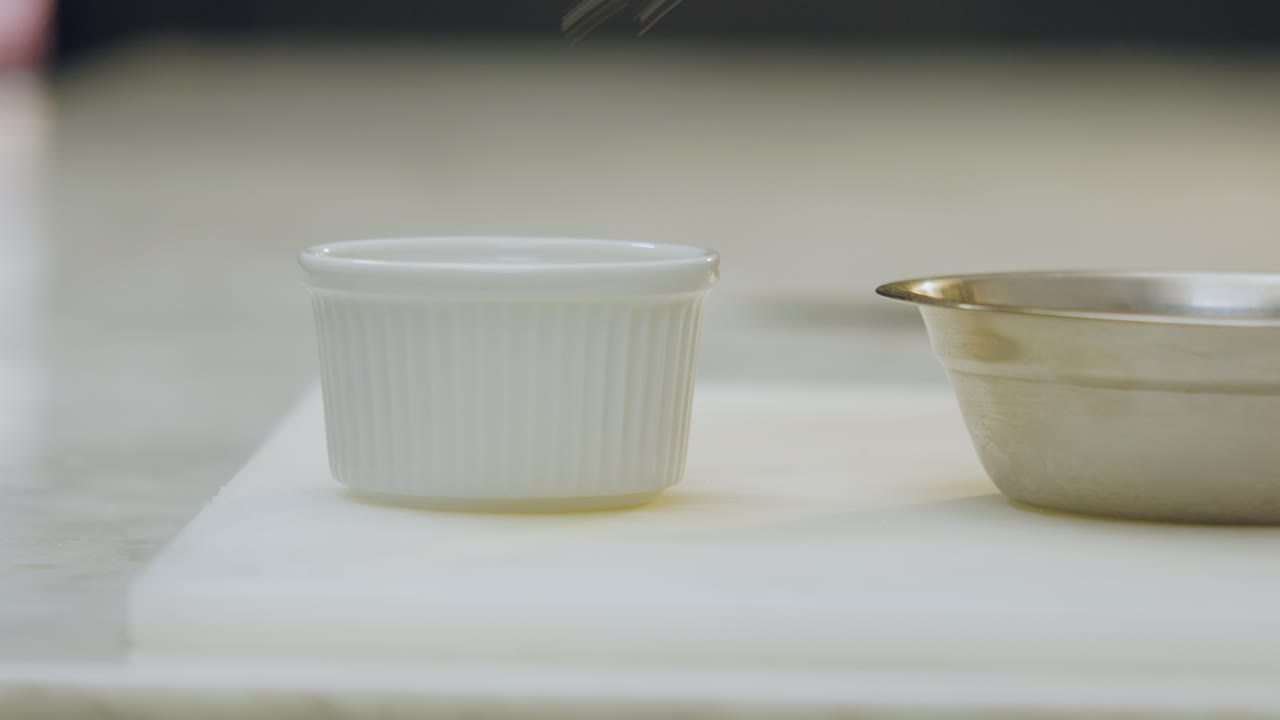 Close-up of a chef using tongs to transfer apple slices from an aluminum mold to a ceramic mold