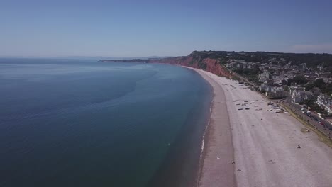 amplia vista aérea de un mar azul, playa de guijarros, acantilados triásicos rojos oxidados y la tranquila ciudad de budleigh salterton