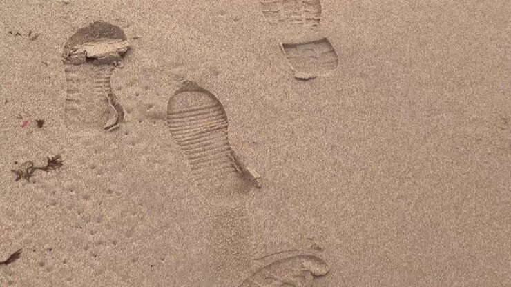 Close-up of a footprint on the sand creating a beautiful pattern on the beach, symbolizing human presence and the ephemeral nature of memories, follow shot