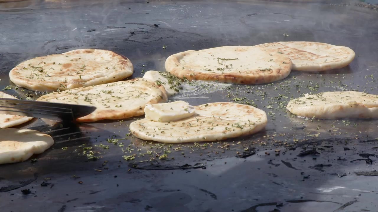 Naanbrød tilberedes på en enorm udendørs grill med krydderurter og ghee