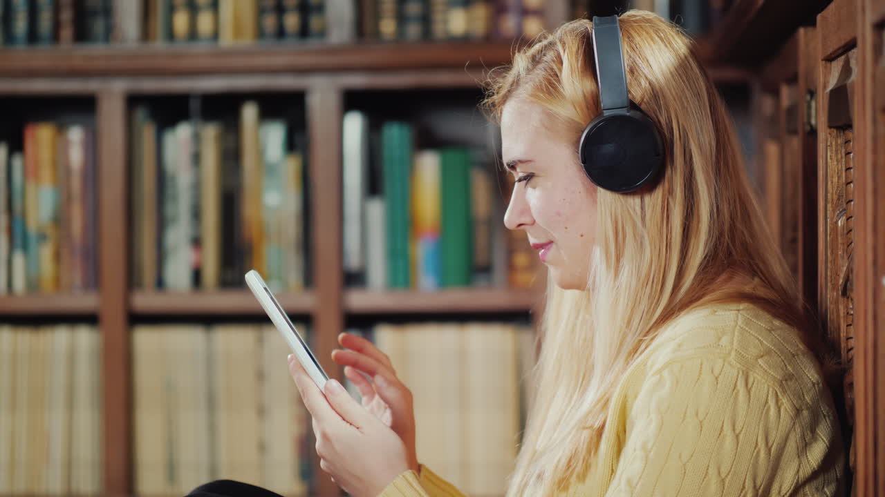 una mujer usa una tableta en la biblioteca de su casa