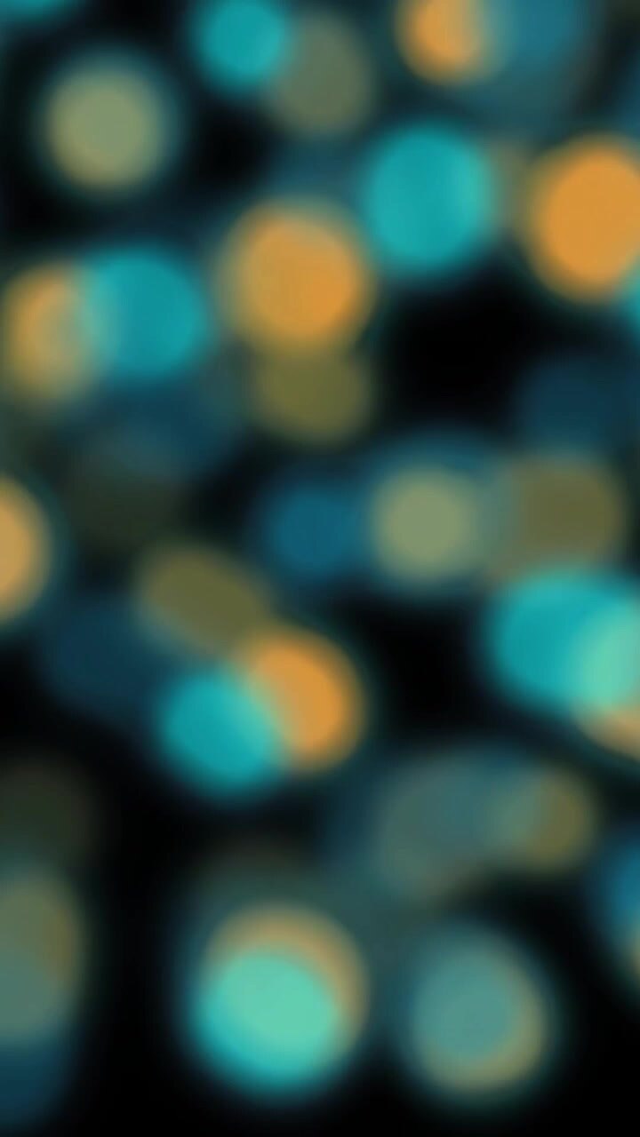 Animation of flashing defocused orange and blue light spots on black background
