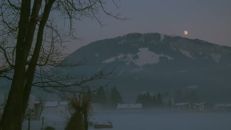 Time-lapse-of-snowy-mountain-while-the-sun-sets-and-the-full-moon-rises-behind-it