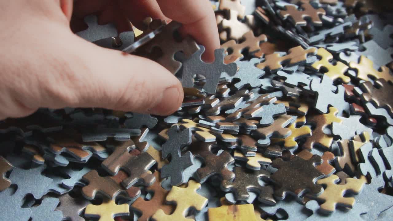 la mano masculina se mueve entre las piezas de un rompecabezas, cámara lenta 120fps