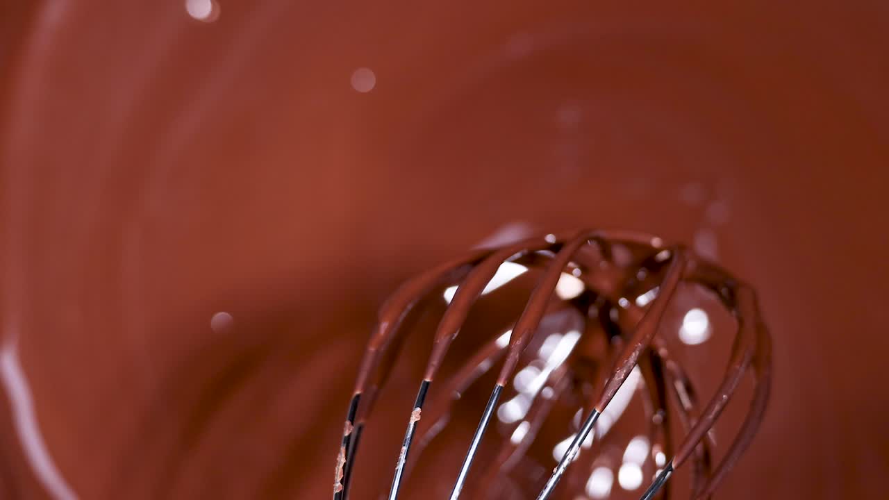 A whisk stirring melted chocolate smoothly