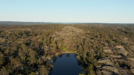 Vista-Aérea-Sobre-Un-Estanque-En-La-Montaña-Rislaaknuten,-Durante-La-Hora-Dorada,-En-Birkeland,-Agder,-Sur-De-Noruega---Dolly,-Drone-Shot