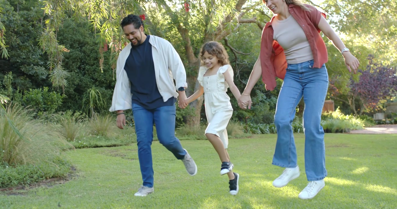 Familia afroamericana entrando por la parte superior del encuadre, caminando ligeramente por un césped soleado, cogidos de la mano para divertirse.