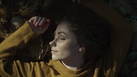 caucasian woman lying at the ground with leaves and enjoying the sun.