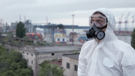 hombre en traje de protección de pie en el techo con vista industrial en el fondo