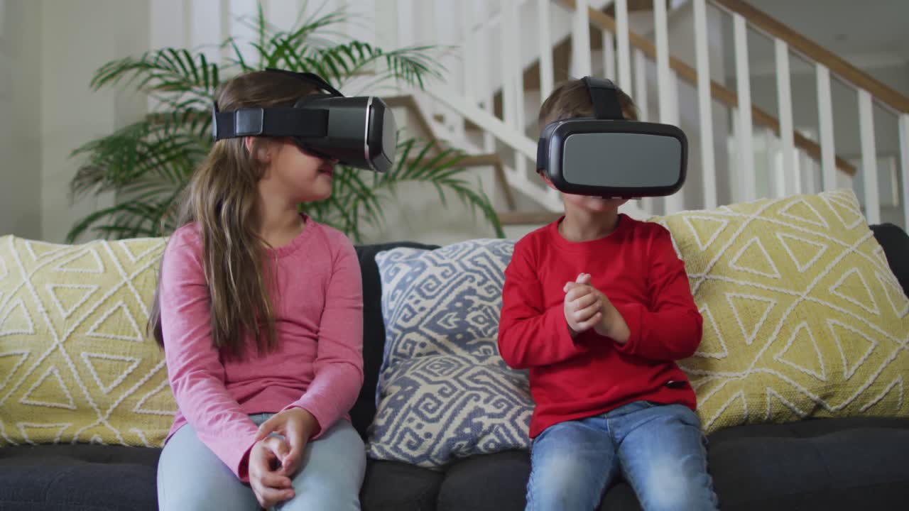 hermanos caucásicos usando auriculares vr, sentados en el sofá y divirtiéndose