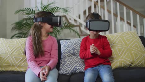 hermanos caucásicos usando auriculares vr, sentados en el sofá y divirtiéndose