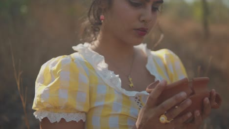 disparo en cámara lenta de ensueño de una joven y atractiva mujer india mirando hacia abajo la cerámica rota en sus manos, poca profundidad de campo
