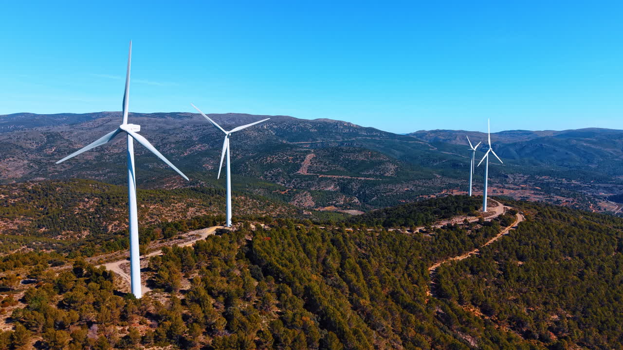 Madrid, Espanha, 8 de agosto de 2025: Turbinas eólicas brancas em cumes verdes sob céu azul. Vários geradores eólicos em cima de colinas cobertas por árvores verdes e arbustos em condições ensolaradas