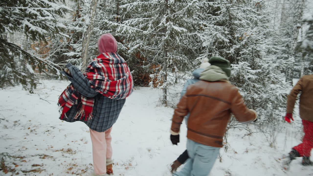 Amigos alegres correndo na floresta de inverno