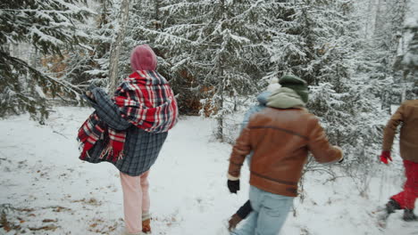 joyful friends running in winter forest