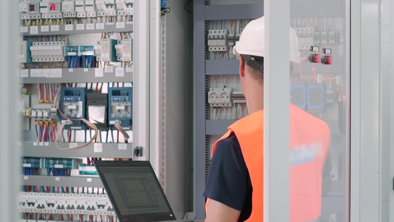 el ingeniero eléctrico que trabaja comprueba la tensión de corriente eléctrica y la sobrecarga en la parte delantera del gabinete del centro de carga o de la unidad de consumo para el mantenimiento en la sala principal del sistema de distribución de energía.