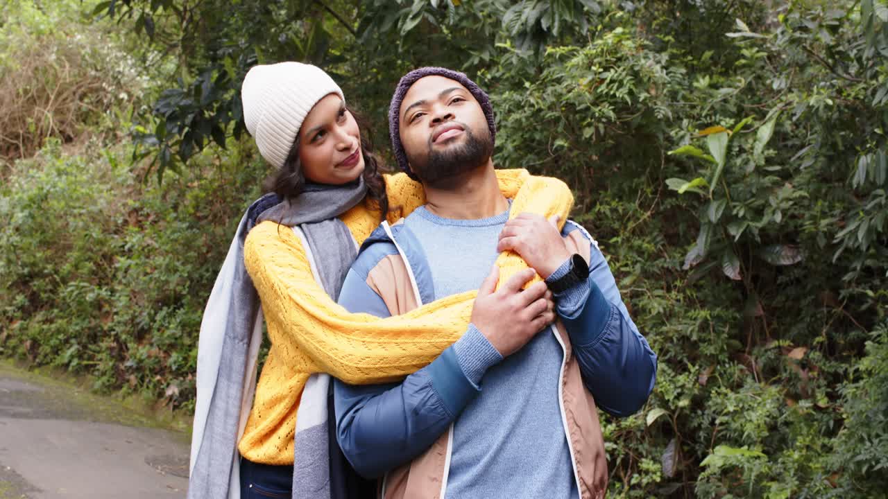 Couple walking on trail wearing scarf as woman hugging partner shoulders expressing affection