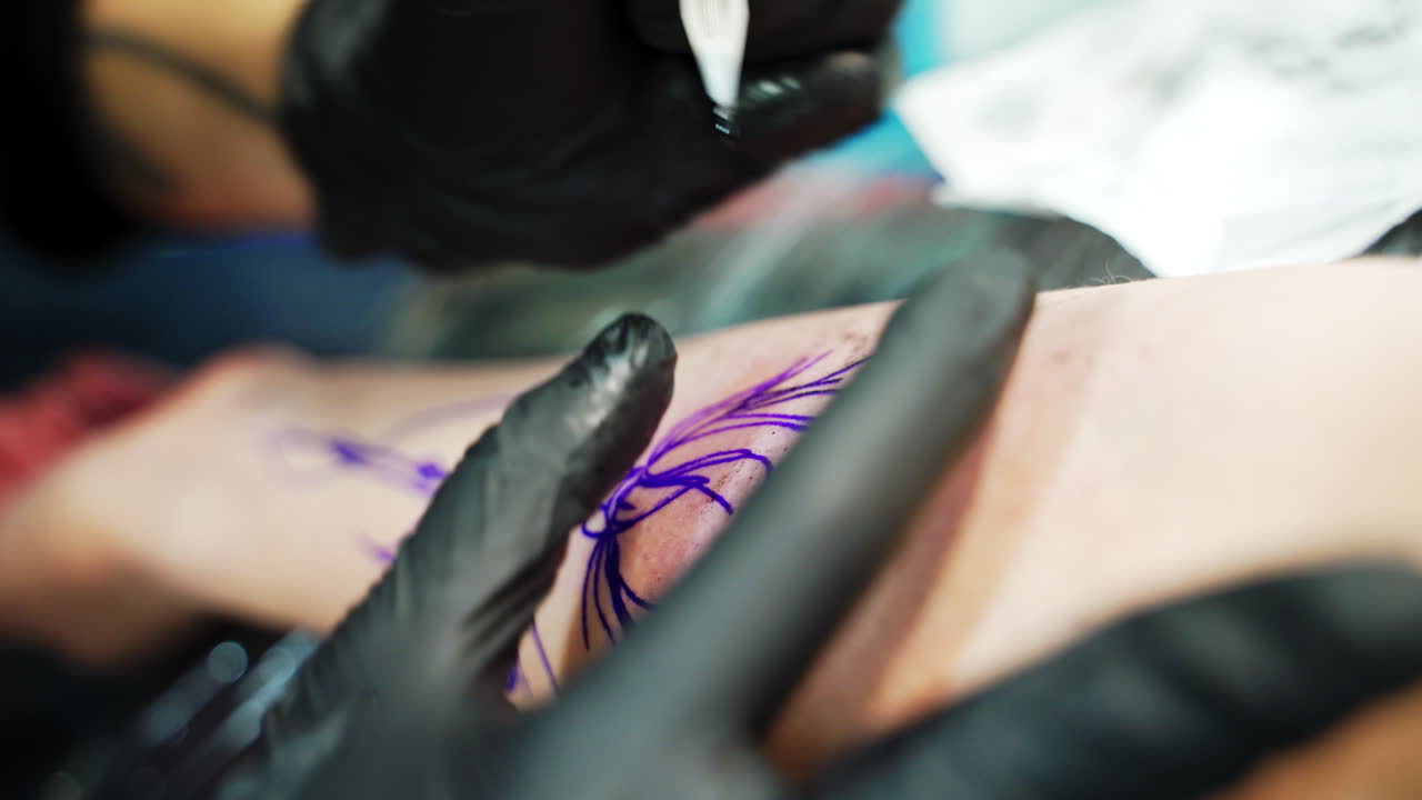 Gloved hands use special machine for tattoos. Putting the tattoo on the hand. Close up.