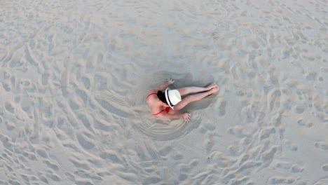 top aerial drone view of woman in swimsuit bikini relaxing and sunbathing beach near the ocean