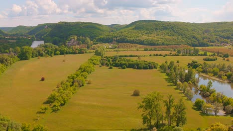 grassy fields, trees and mountains seen from the beynac castle of dordogne valley in beynac, france. -wide shot