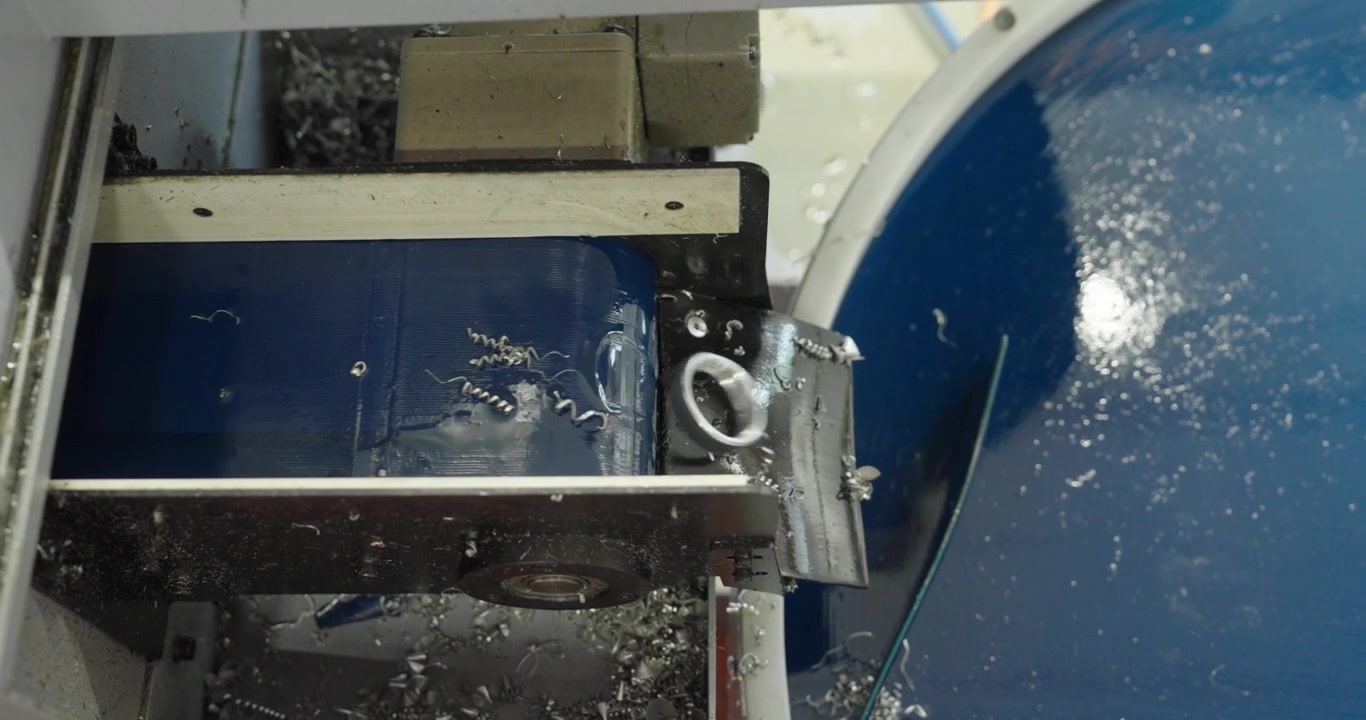 Close-up of an industrial conveyor belt transporting precision metal components inside an automated manufacturing machine during factory production.