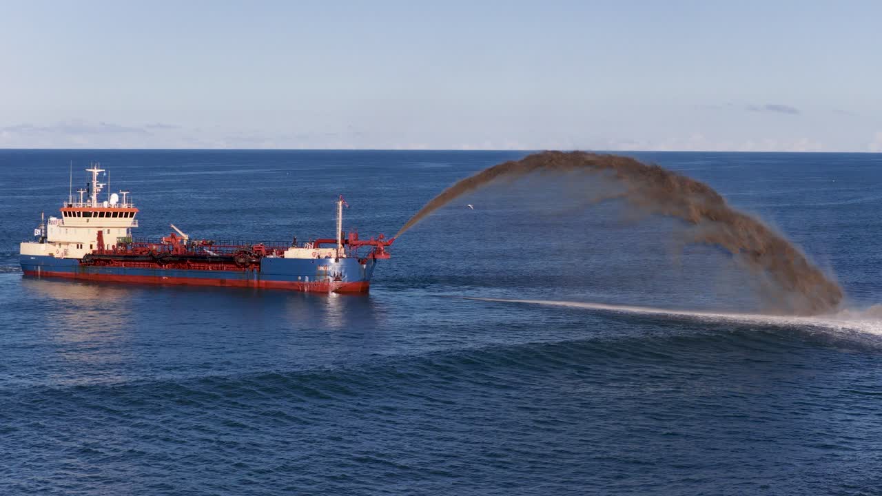 A dredging vessel pumps sand into the ocean, combating erosion under clear skies on the Gold Coast, Australia