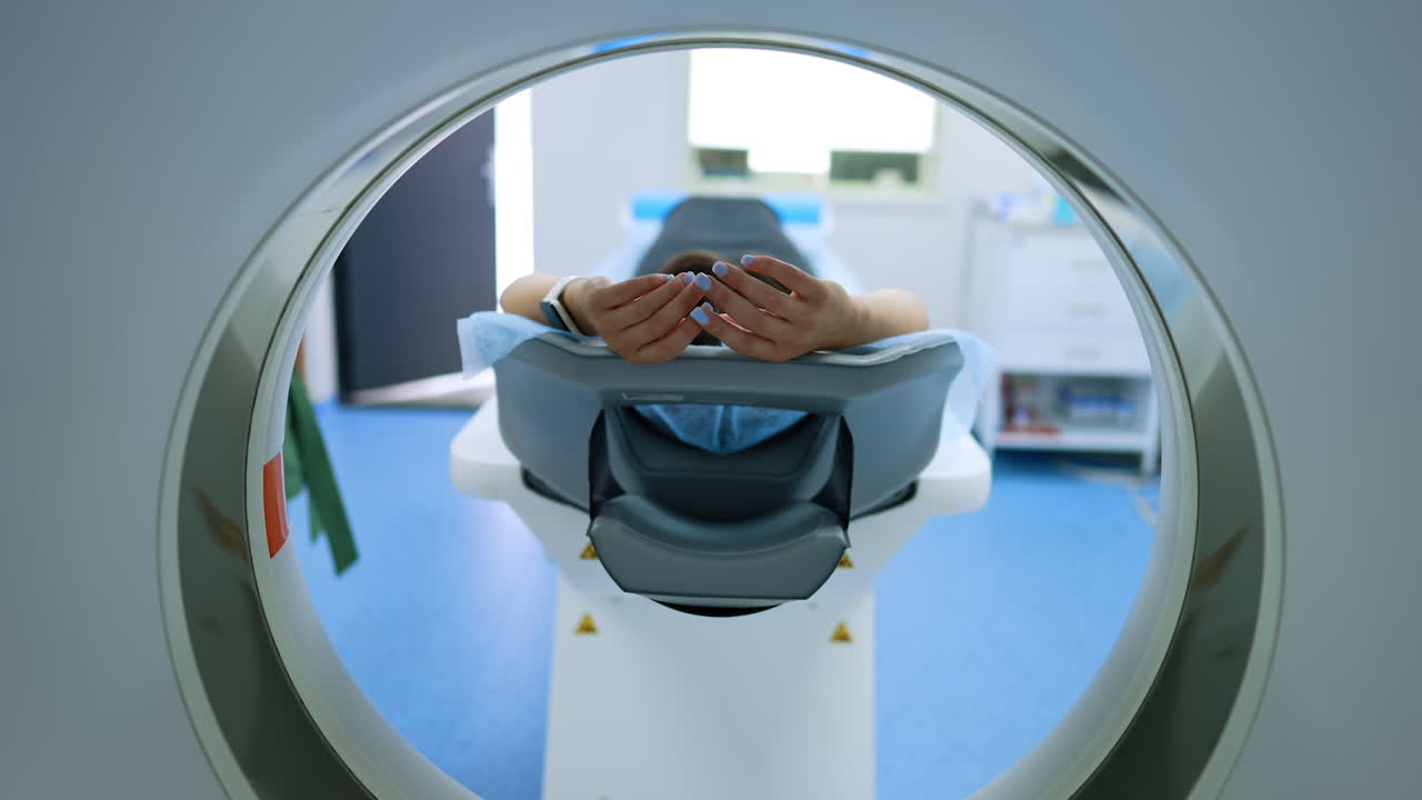 Kyiv, Ukraine, 2 August 2025: Patient lying inside a hospital MRI machine. View from inside the tomography tunnel focused on the hands of the lying female patient