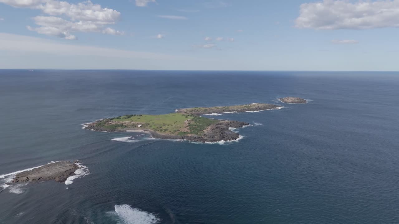 포트 블라 (port kembla) 해안에서 풀과 관목이 있는 외의 낮은 열대 바위 섬으로 가는 공중 도리 (aerial dolly)