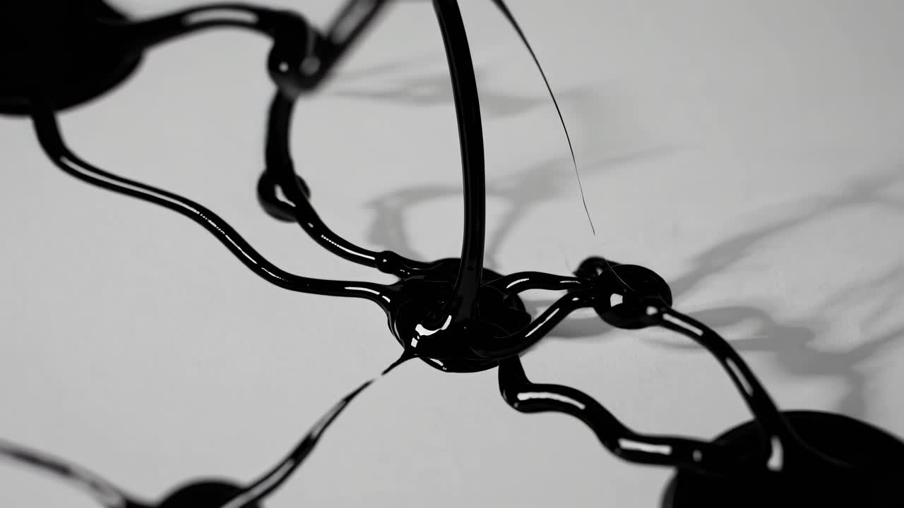 Abstract video of black liquid splashing on a white surface, captured from a side angle